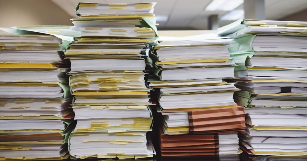 積み重なった書類と本が並ぶデスク