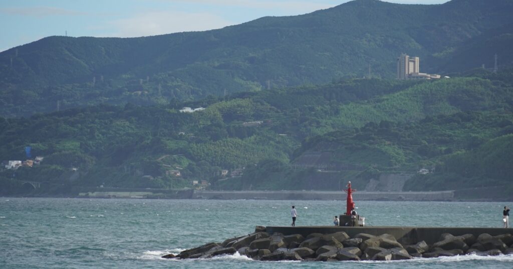 岩礁の上に立つ赤い灯台と青い海