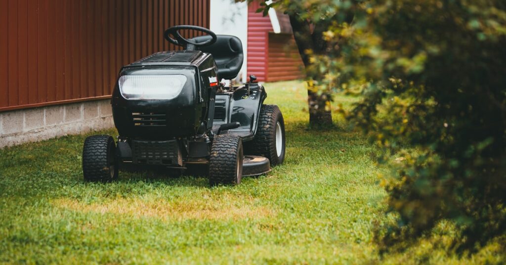 緑の芝生の上を走る黒い乗用芝刈り機