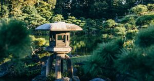 池の中央に立つ東屋と木々に囲まれた静かな日本庭園